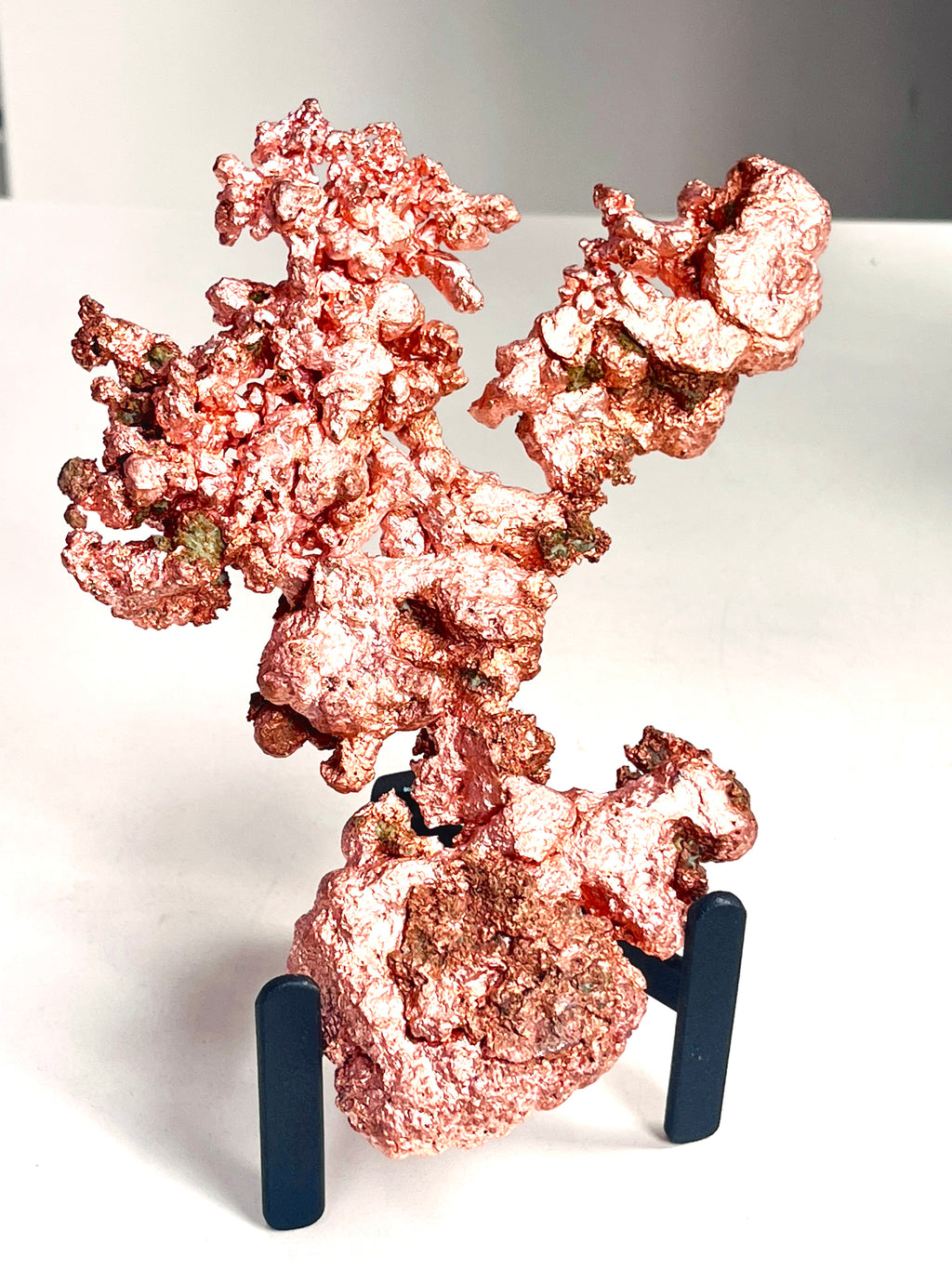 A metallic copper-colored decorative sculpture or mineral specimen displayed on a small black stand against a plain light background.