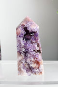 Amethyst crystal tower on a white surface with a neutral background