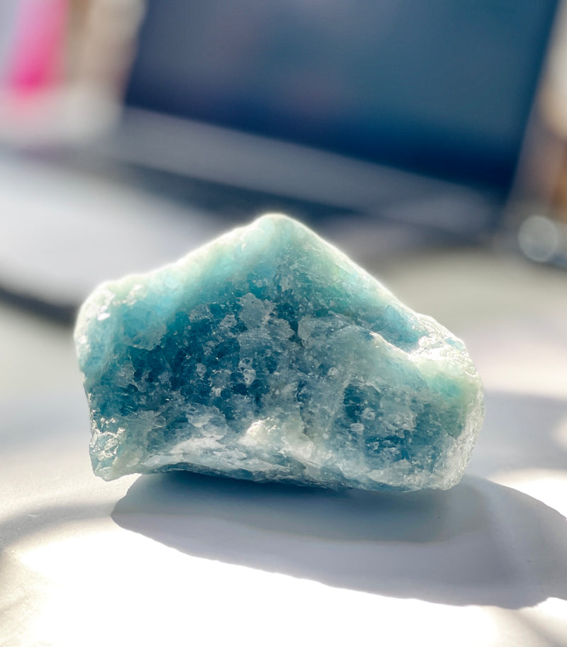 A large aquamarie on a desk with natural sunlight on it 