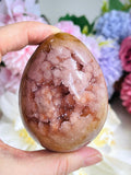 Person holding a polished gemstone with a floral background