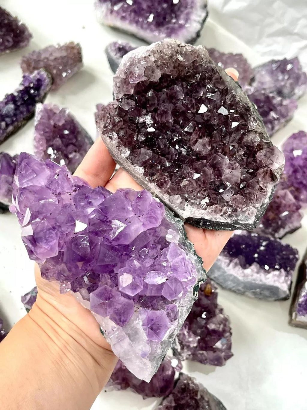 Close-up of amethyst crystal clusters with a hand holding one.