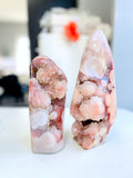 Two crystal-like objects with a pink and white marbled pattern on a blurred background.